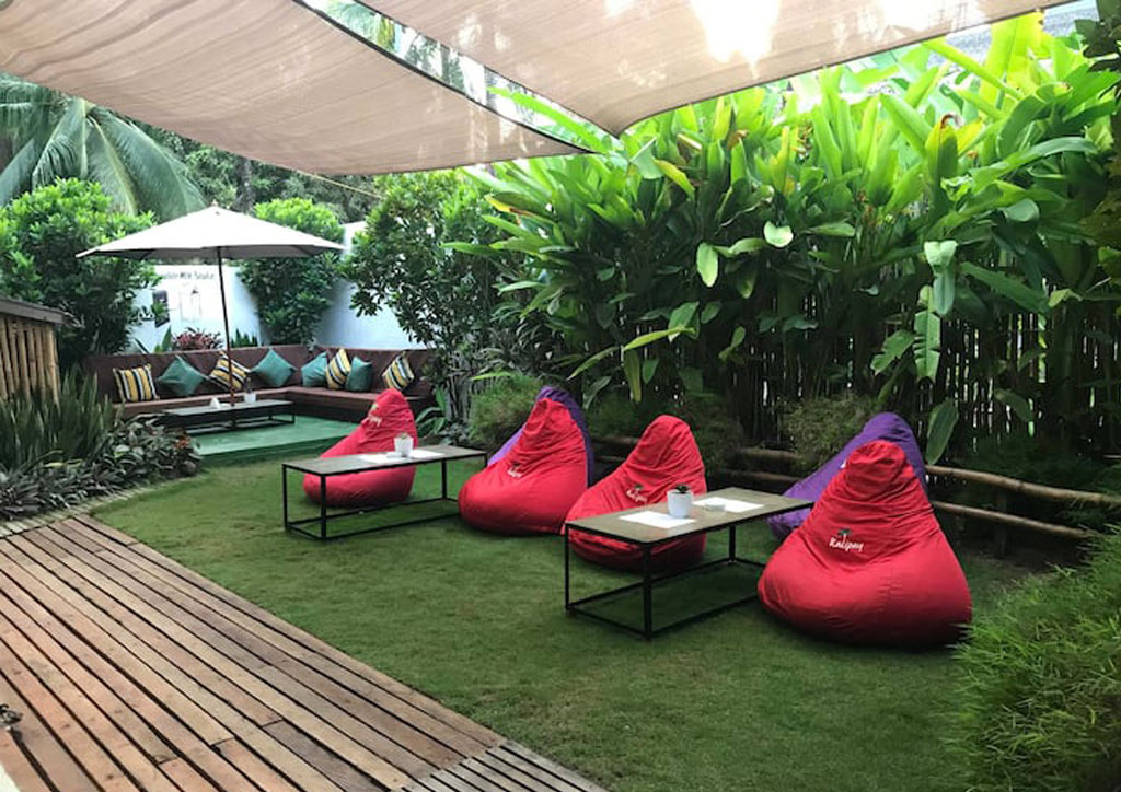 Exterior area with red bean bags, wooden decks and grass.