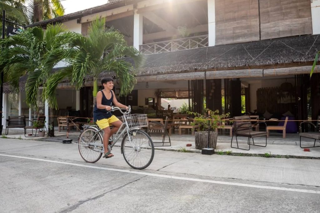 a boy riding a bicycle in front of Kalipay Resort Siargao