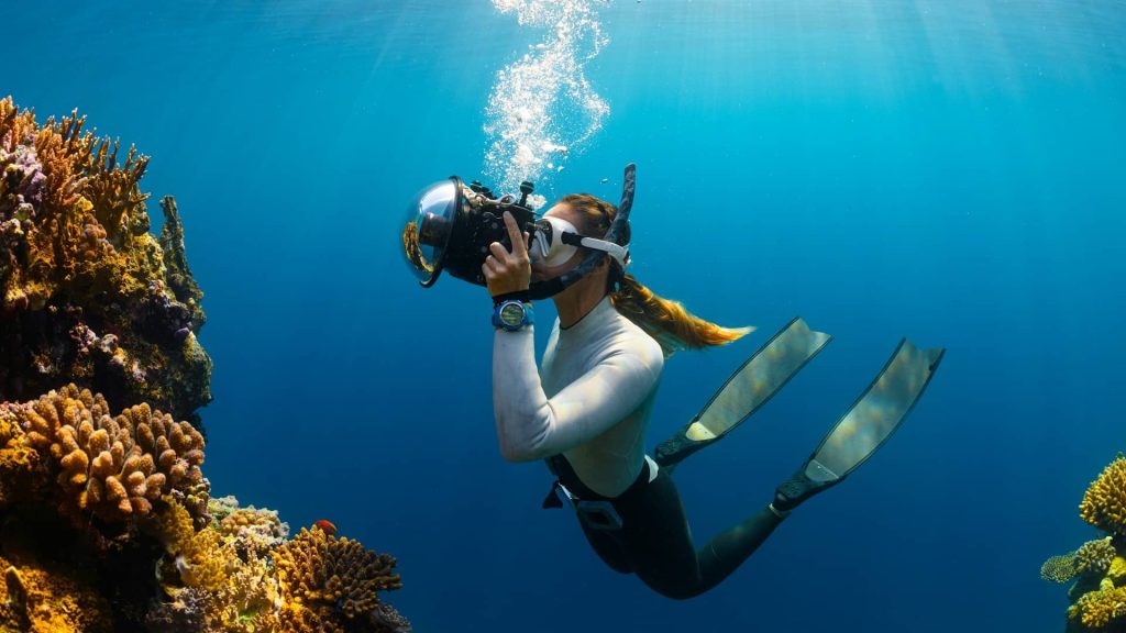 a woman scuba diving with a camera in siargao