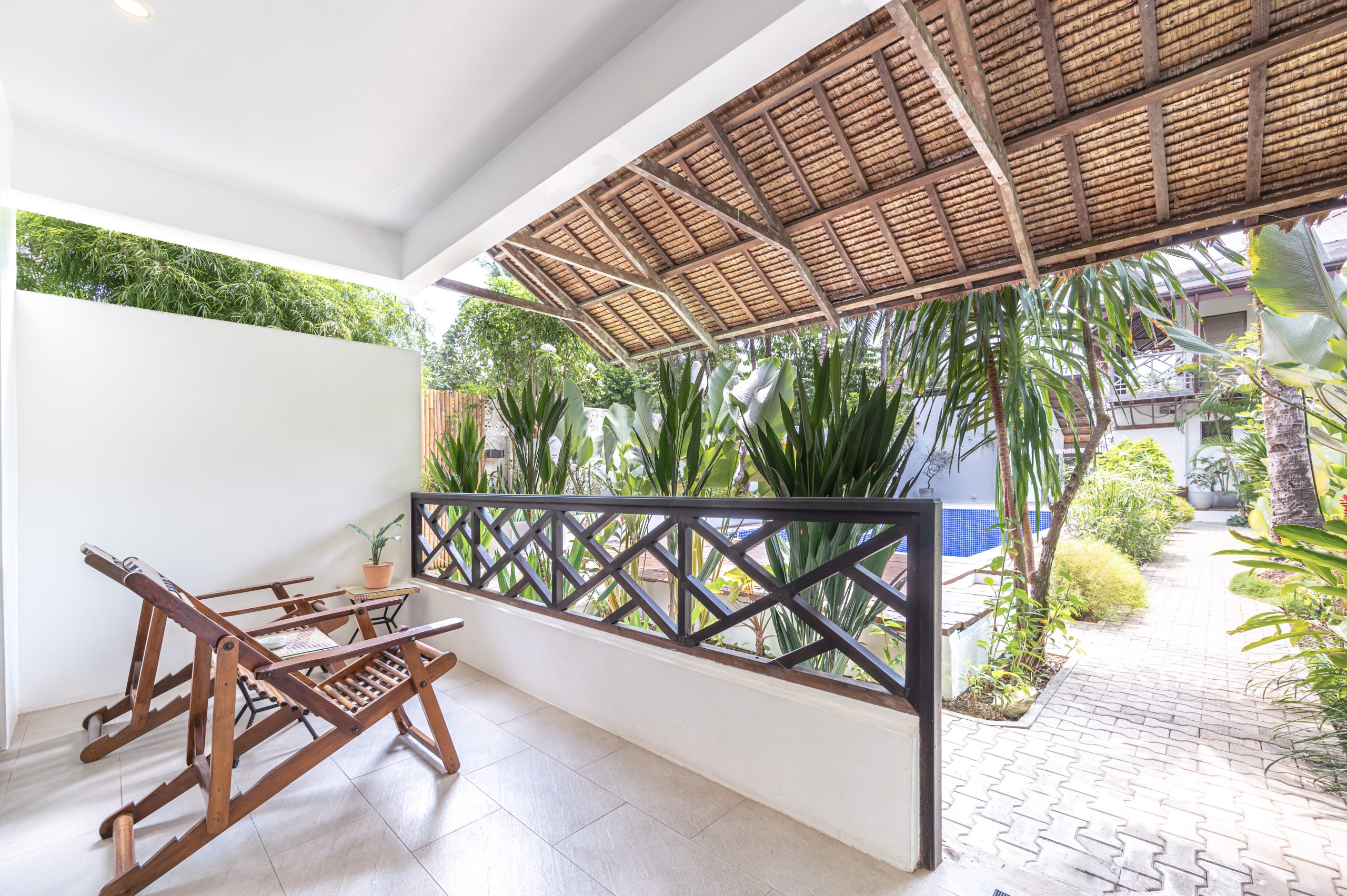 Covered balcony seating beside the tropical garden